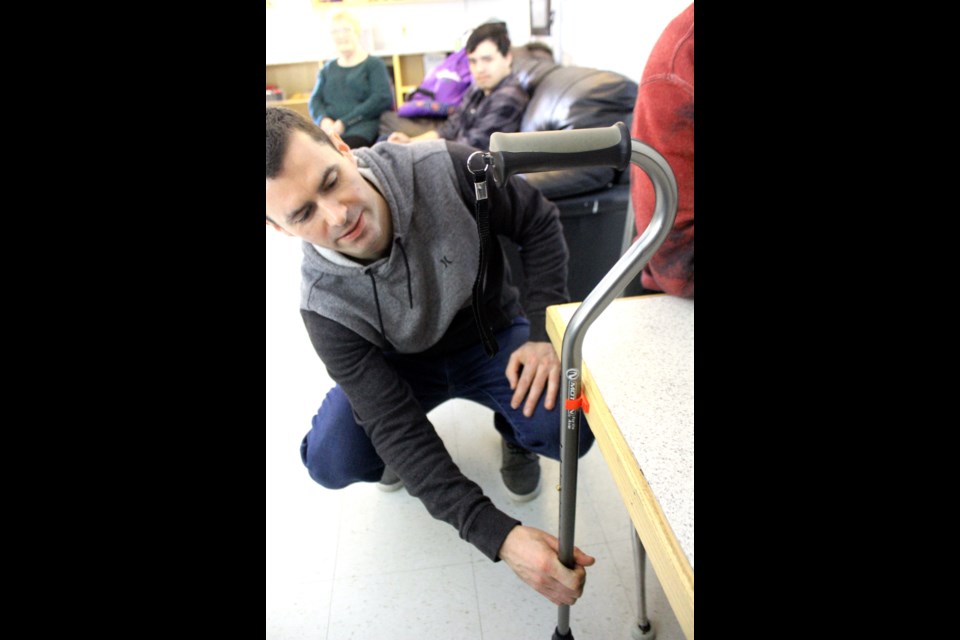 Many Faces Education Centre teacher Dan Dillon shows off one of the items his class created for Jubilee Residence seniors with a 3D printer – cane clips, designed to keep canes, brooms or other items from falling to the ground. - PHOTO BY ERIC WESTHAVER