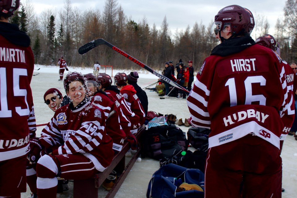 Alec Malo gets a faceful of slush from teammate Dane Hirst while sitting on the bench. During down times in the game, players threw slush, playfought and even threw snowballs. - PHOTO BY ERIC WESTHAVER