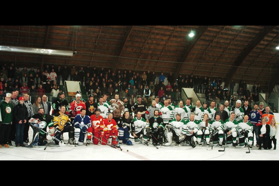 Teams, coaches, and staff gather for a group shot at center ice.