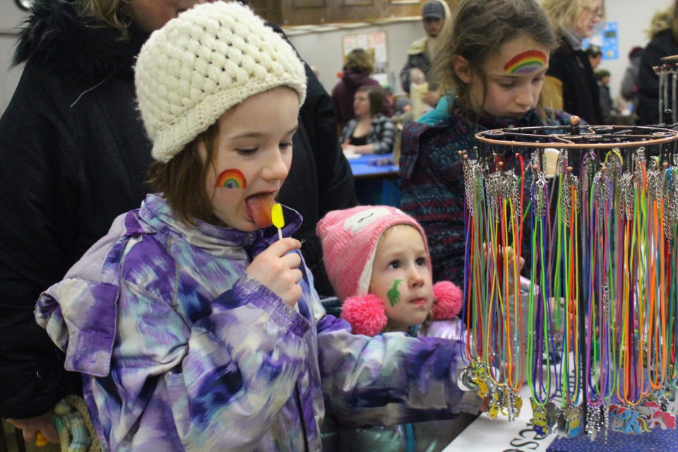 COLOURFUL CONCERNS - Abby, Iris and Lily Kendrick take a look at a stand of magnets, bracelets and charms at the Bust the Winter Blues craft sale March 7. - PHOTO BY ERIC WESTHAVER