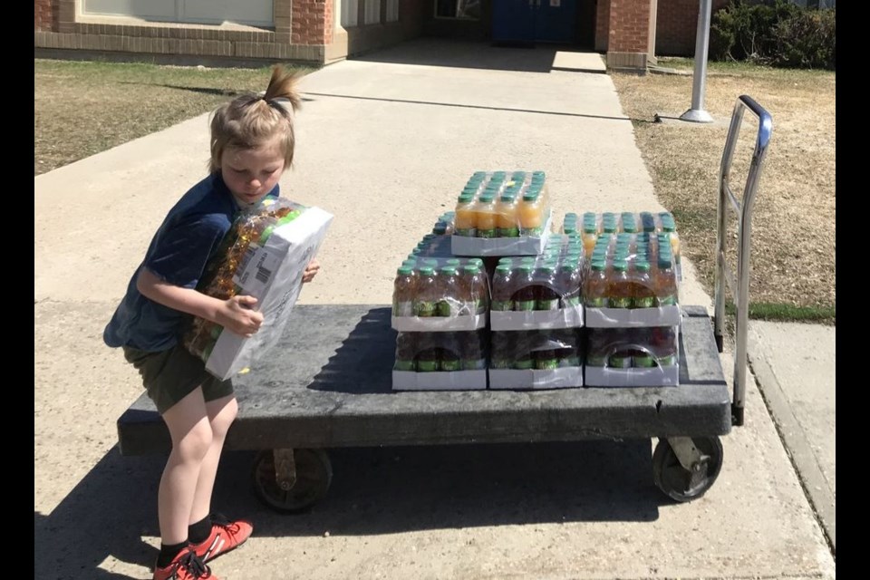 Hutch Nelson helps unload juice donated to the lunch program. His mom, Candice Nelson, one of the organizers, quipped: "Hard to find help when you are only allowed to hang out with people from your household!"