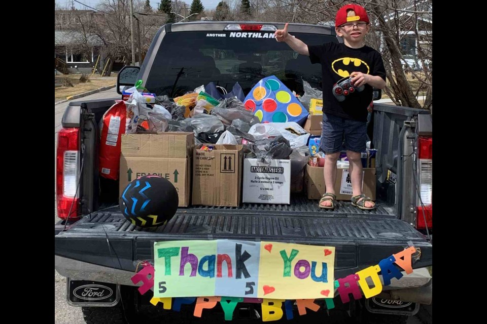 Nash Neufeld shows off food and goods for the Lord’s Bounty Food Bank on his fifth birthday. Neufeld’s socially isolated birthday celebration included a lengthy parade of family, friends and members of the Flin Flon Fire Department, along with a donation drive for the food bank. - SUBMITTED PHOTO