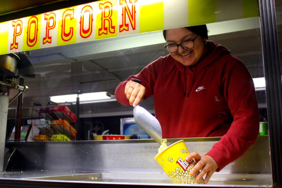 Employee Dilyn Johnson scoops out popcorn at the Big Island Drive-In concession. The concession now holds a maximum of 10 customers and has a defined entrance and exit. - PHOTO BY ERIC WESTHAVER