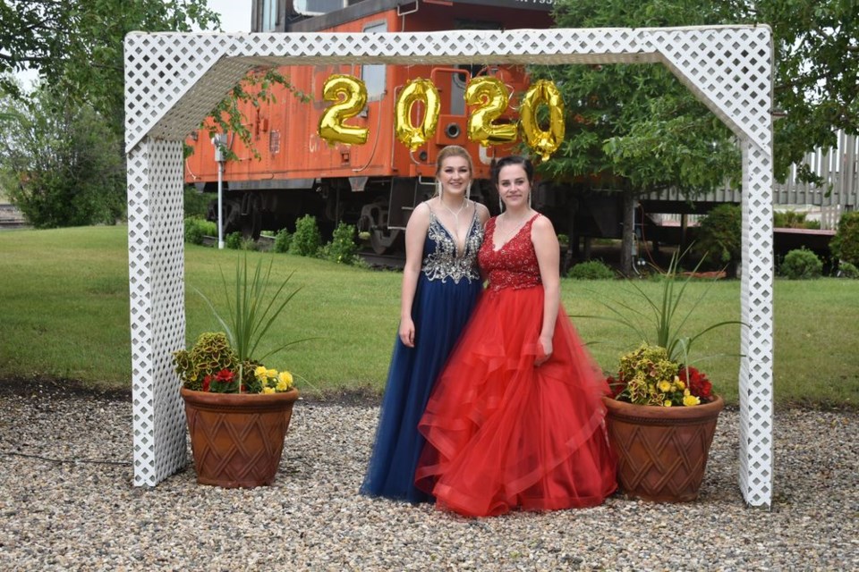 Dressed in formal wear, KCI graduates Brooke Schwartz, left, and Samantha Chernoff were photographed under a 2020 banner at Trackside Garden on June 29.