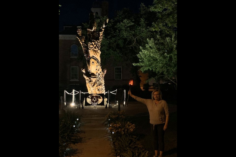 Marlys Collins stands in front of the Estevan Soldiers Tree monument with her Canadian Remembrance Torch. The photo has garnered national attention. Photo submitted