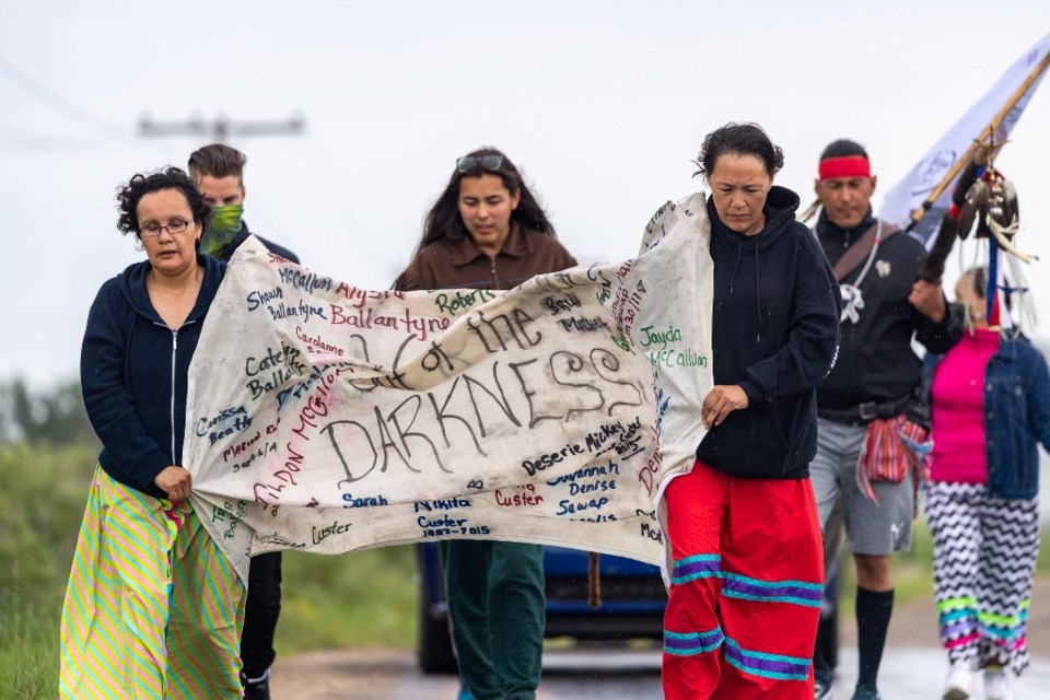 Tristen Durocher with two women carrying a banner reading
