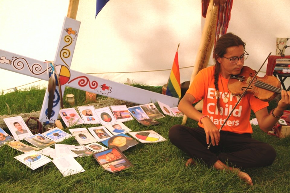 Tristen Durocher sits among the faces of family members lost to suicide in his teepee erected in Was