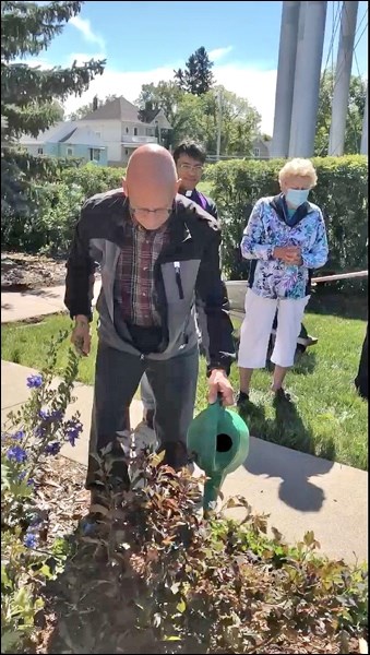 Caretaker Craig Treiber waters the newly planted shrub commemorating the100th year of the national C