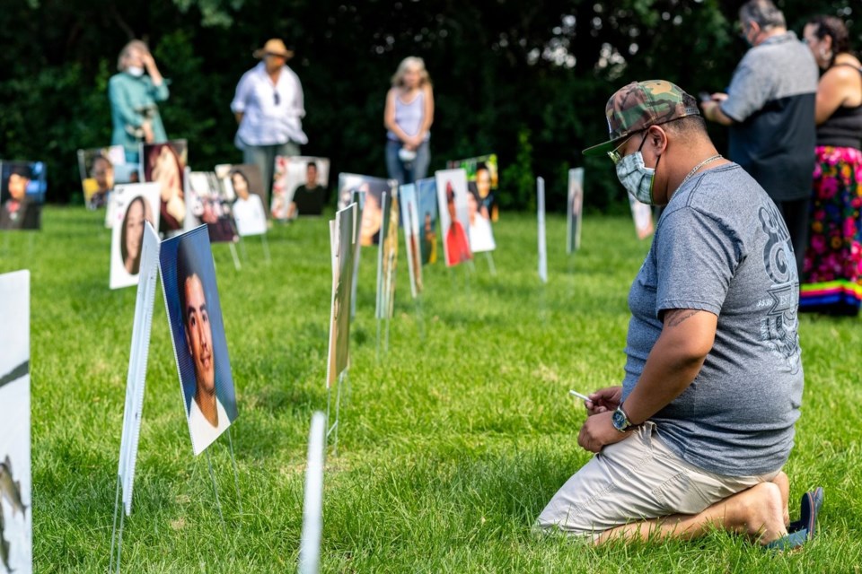 A grieving man in Regina makes a tobacco offering as he looks at photos of northerners who took their own lives. Photo submitted by Brandon White