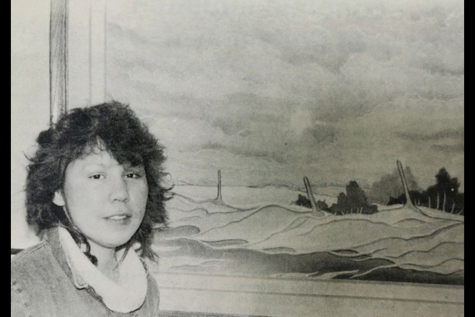 As part of her job in 1987, Nellie Straightnose tended to the Kamsack Art Gallery. She was photographed in front of one of the pieces painted by Yorkton artist, Brenda Roberts.