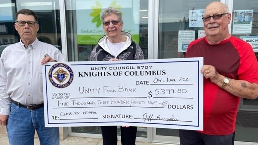 Richard Colbow, Unity Knights of Columbus member, presents a donation of $5,399 to Unity Food Bank volunteer Tomi Watt, along with Knight George Ehresman. Photo submitted