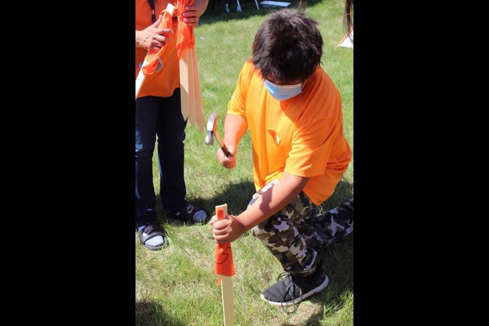 Children from the Cote First Nation who attended the ceremony on June 16 were invited to acknowledge the victims of the Kamloops residential school by taking part in grounding orange flags. Photo by Amy-Lynn Costigan.