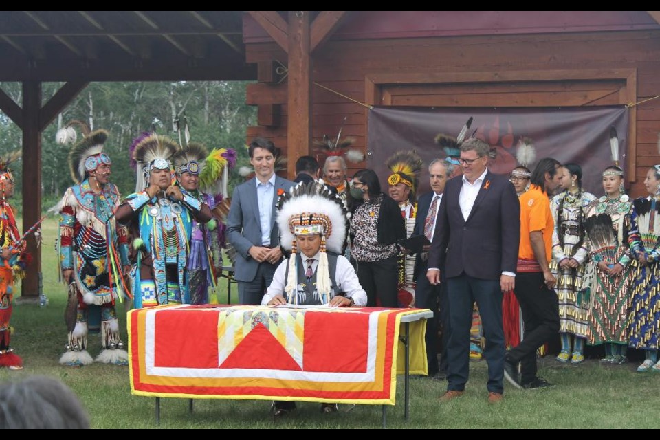 Chief Cadmus Delorme (seated), Prime Minister Justin Trudeau (L) and Saskatchewan Premier Scott Moe (R) gathered at Cowessess First Nation to sign the agreement transferring power over child services back to the Indigenous council.