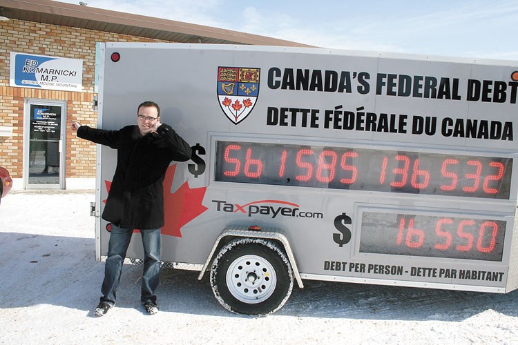Colin Craig, prairie director of the Canadian Taxpayers Federation, indicates with his hand that taxpayers ought to phone MP Ed Komarnicki about the ever-growing federal debt, during a visit with the federation's federal debt clock to Weyburn on Mar. 8. According to government figures, the debt is growing by $1,400 per second, or $124 million a day; the Taxpayers Federation wants voters to be aware of just how high the number is growing, as this calculator is continually adding the new figures at a rate of $1,400 per second. The federation is hoping to make citizens aware of how big the debt as the federal budget comes up on Tuesday, Mar. 22, followed by the provincial budget on Wednesday, Mar. 23.