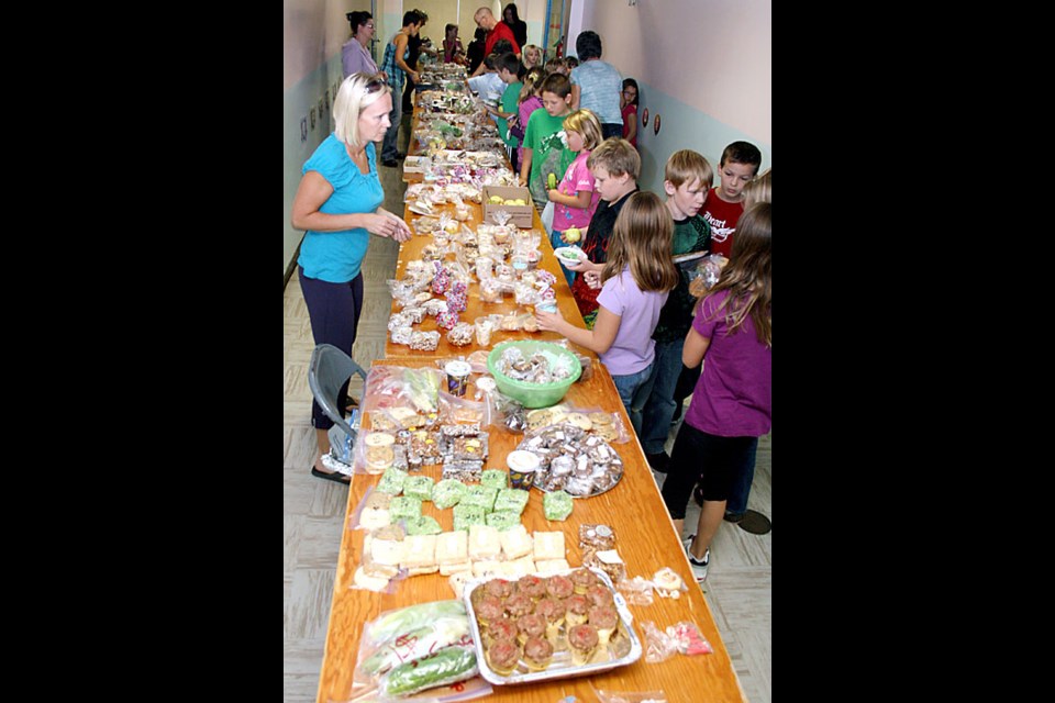 Parent volunteer Bonnie Ernst, left, waits for Grade 4 students to make up their minds about what they want to buy at the annual fruit, veggie and bake sale held on Friday morning at Haig School. At right, the group of students include Kevin Pattyson and Taylor Cameron at the table, and Keenan Russell, Mackenzie Rogal and Hannah Cole at right. The proceeds will go towards the purchase of supplies for the benefit of the students at Haig.
