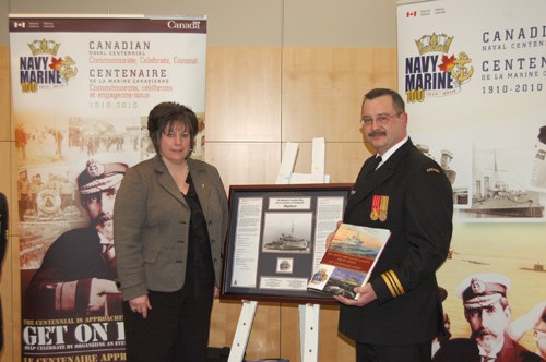 (L-R) Mayor Debra Button received a framed pictorial history of the HMCS Weyburn on behalf of the City from Lieutenant Commander Corey Thiemann during a Royal Canadian Navy centennial celebration held at City Hall in February.