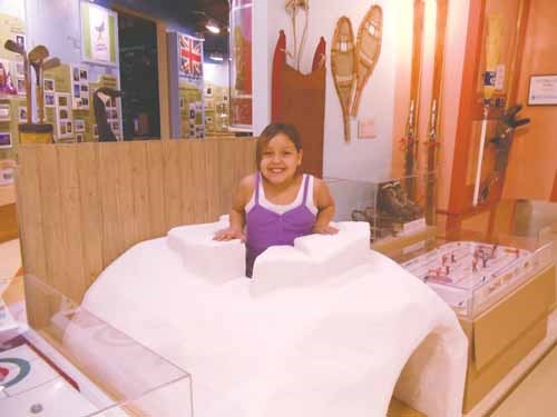 Sarcee Quewezance demonstrates how to travel through the new quinzee display at the museum.