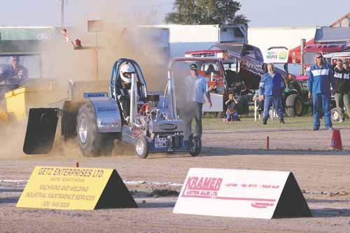 A mini tractor kicks up some dirt.