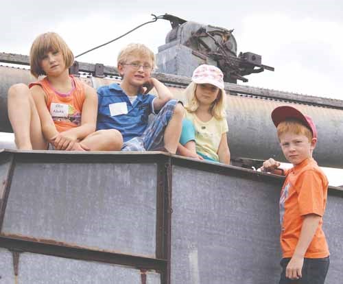 Erin Novak, Kayden Curtis, Ashlyn Gnyp, and Keanen Gnyp perch on an antique threshing machine at Cherrydale Golf Course.