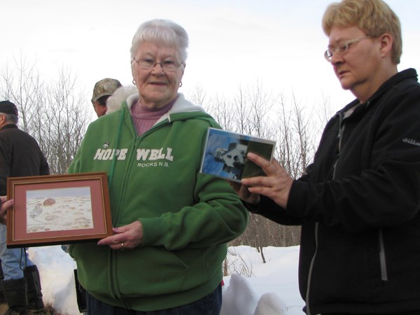 Ruth Hrynewich and Darlene Woloshyn examine photos, keepsakes and reminisce. Hrynewich holds a painting done by famous Whitkow artist Ann Harbuz.