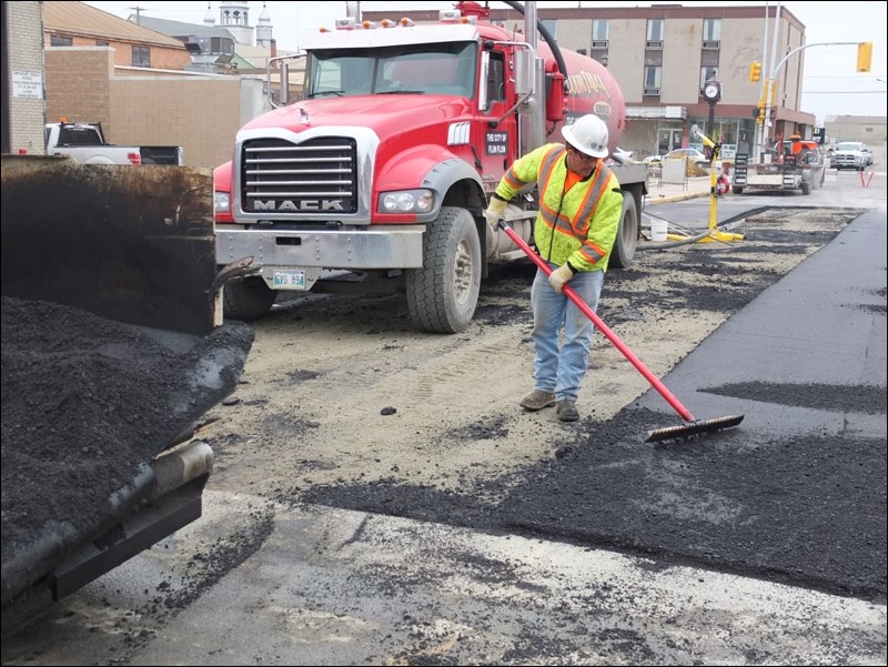 Asphalt rake in hand, Mark Whitford last week helped smooth a new layer of road on First Avenue, in front of the fire hall and Pioneer Square. The asphalt covers a section of road dug up as part of infrastructure work.