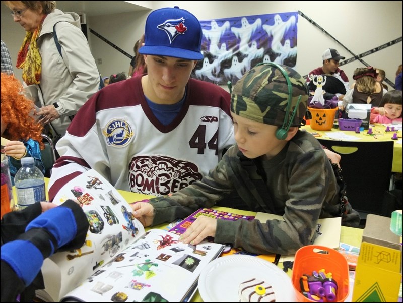 Bombers blueliner Brandon Masson watches as Oliver Atchison, 6, goes through a book of stickers at the Flin Flon Public Library’s Lego Halloween party on Monday. The Bombers were on hand to help costumed kids enjoy a spooktacular good time ahead of the big night of trick-or-treating.