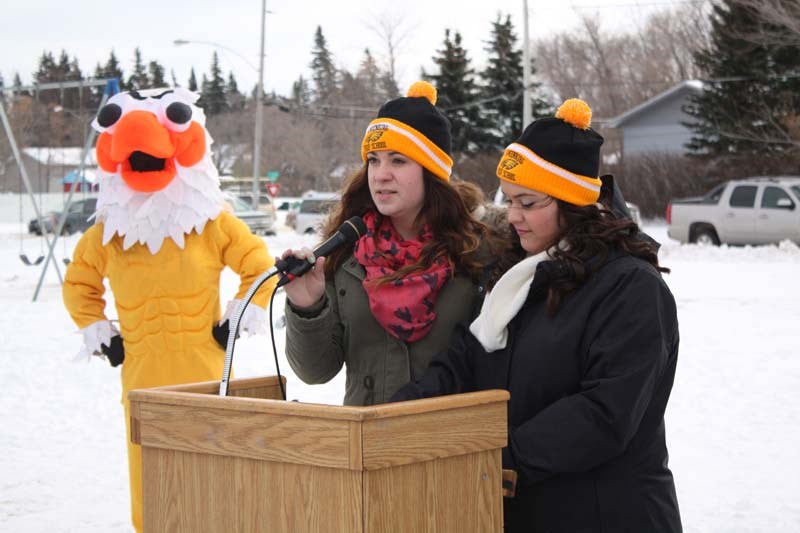 Grade 10 Langenburg High School students Alanna Decorby and Breanna Popp represent the class of 2017, the first that will graduate from the new K-12 facility, at the ground-breaking ceremony December 5 while the school’s screaming eagle mascot clowns around in the background.