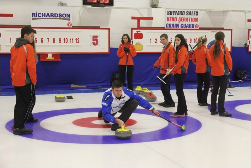 Regina native Braeden Moskowy (third, Team Carruthers) demonstrates how to properly take off from the hack as the YRHS mixed curling team watches.
