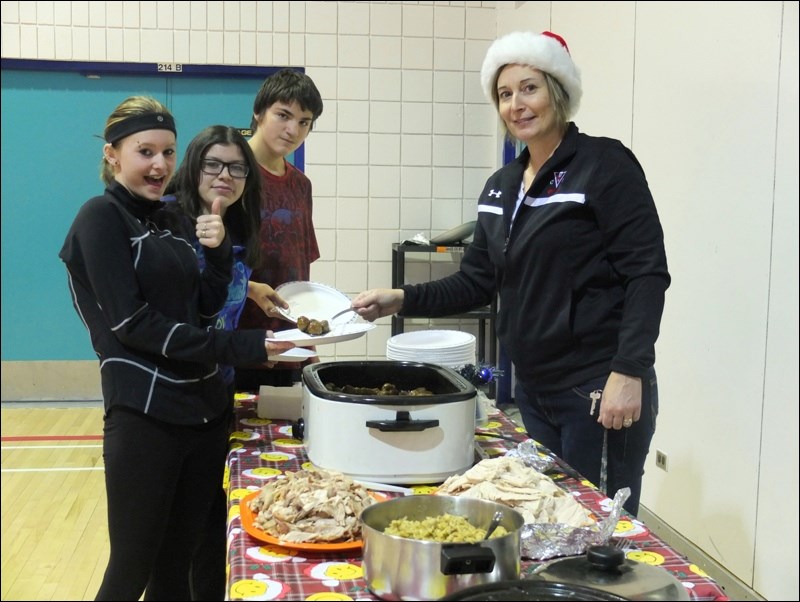 Many Faces Education Centre hosted its annual Christmas luncheon feast Wednesday in the school gymnasium. Pictured (from left) students Brooke McIntyre, Brianna Francoeur and Matthew McDermott wait in line as Patty Korchinski, vice-principal of Many Faces and Hapnot Collegiate, serves turkey, meatballs and assorted fixings. Among the other guests was Flin Flon MLA and former Many Faces teacher Clarence Pettersen.