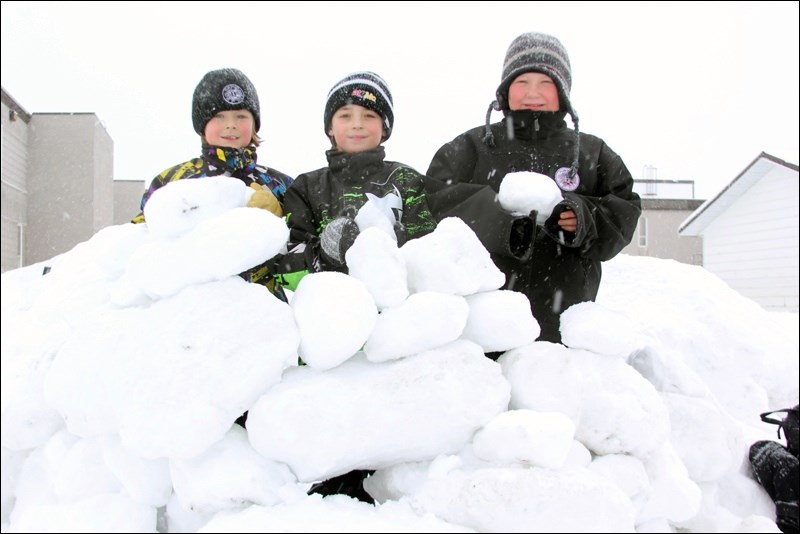 Friends Mason Clement (left), Jacob Kuzmiak and Paxton Dareichuk worked on their snow fort Wednesday after  nearby Creighton Community School was dismissed for the day. Enjoying the snowy weather, the boys repaired damages the fort sustained during the school day.