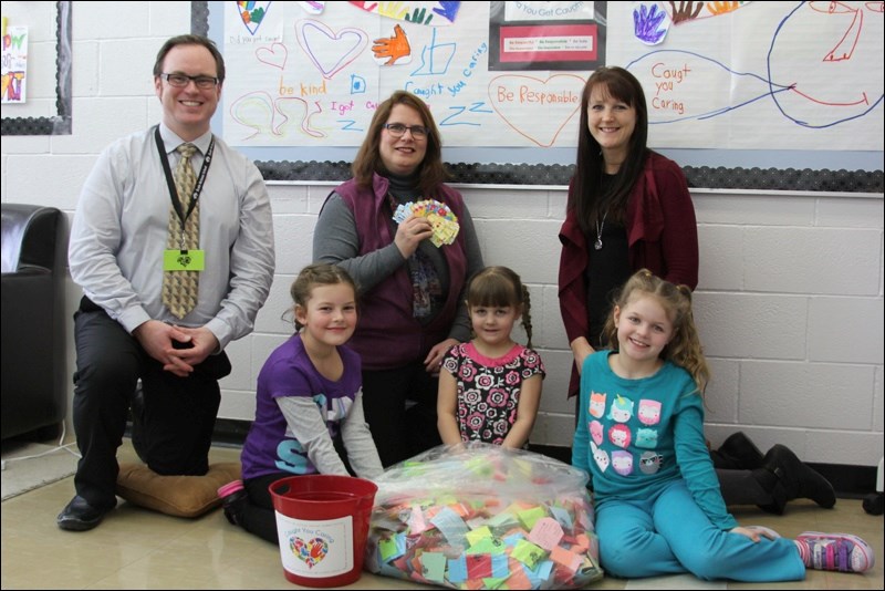 Hailey Sapergia (front, from left), Lydia Alexander and Cassidy Alexander collected Caught You Caring nomination forms from École McIsaac School classrooms. The girls, with the help of Kaleb Sapergia, designed posters for the school’s Caught You Caring campaign, which encourages students to be helpful and kind.  Nomination forms will be accepted until June, when a draw will be held. Parent council treasurer Fran Whitbread (back, centre) presented McIsaac principal Steve Lytwyn and guidance counsellor Carrie Alexander with $250 for the campaign. The council raised $741 at its Christmas grotto sale and donated $250 in gift cards, with the remainder to be put toward new balls for the school’s playground.