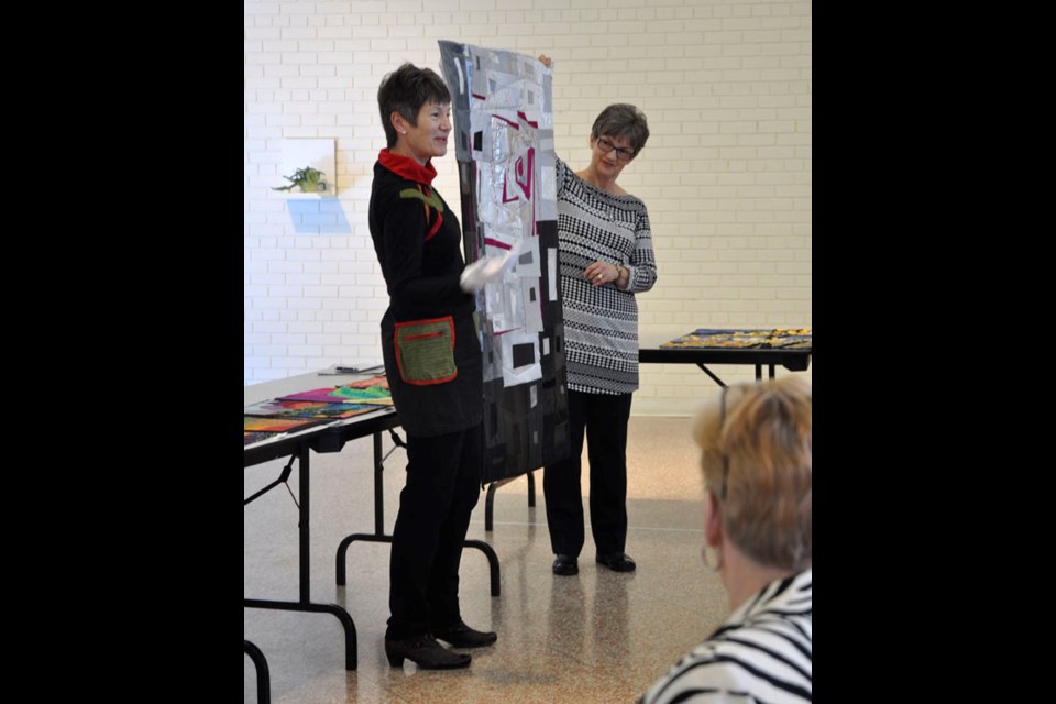 Left, Himsl, assisted by Irene Sack of the Rivers’ Edge Quilt Guild, displays one of her own quilts.
