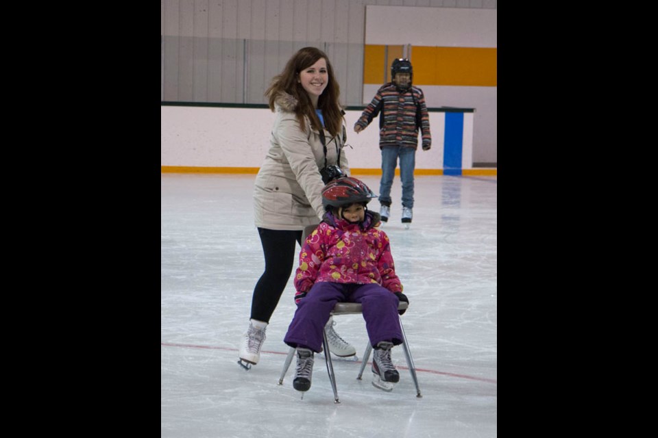 A youngster is all smiles as her mentor spins her around the ice on a chair during an outing with the Arcola School Mentorship Program.
