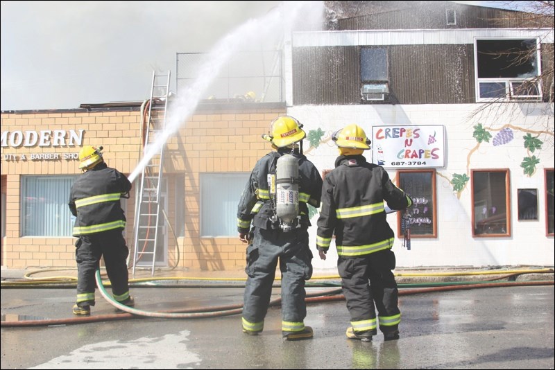 A firefighter douses the front of Crepes N Grapes.