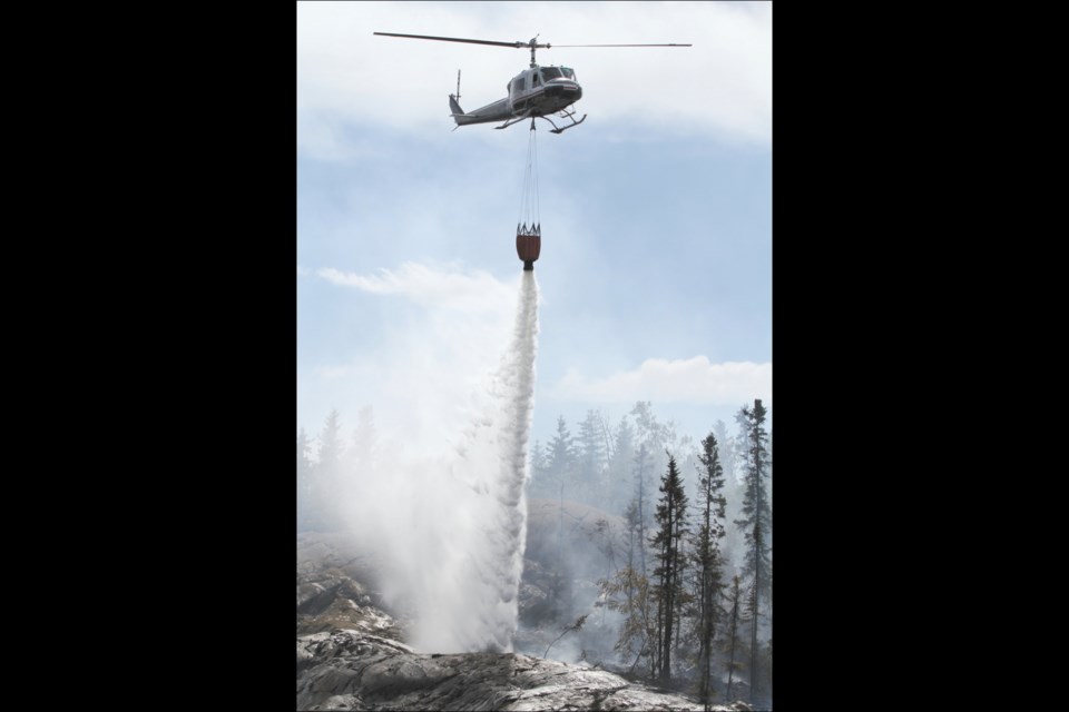 A helicopter drops a load of water onto a wildfire near the Flin Flon ski chalet last Thursday, August 13. Local and provincial crews worked to douse the blaze, which was believed to have been intentionally started.