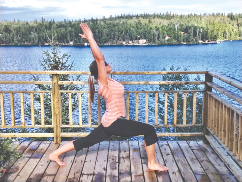 Flin Flon teacher Anna Jardine holds a yoga pose on her deck overlooking Lake Athapap.