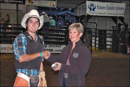 Receiving the eighth annual Edam Indoor Rodeo amateur bull rider buckle from Laura Martin is Evan Matchee of Cochin. Photos by Brenda Pollard