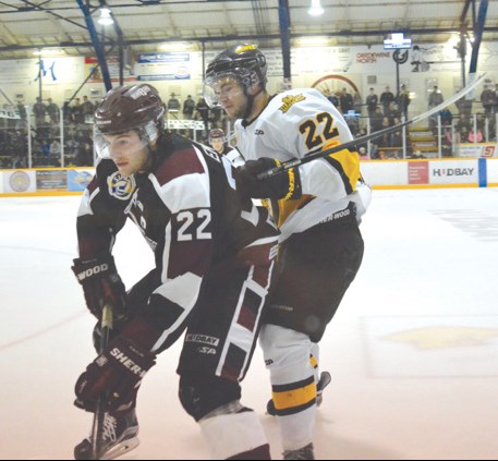 Sporting his team’s new third jersey, Flin Flon Bombers captain Tyson Empey (left) and Nipawin Hawks winger Kris Spriggs go for the puck during Flin Flon’s home opener last Saturday, Sept. 19. The Bombers opened 2015-16 with a regulation loss and a shootout loss.