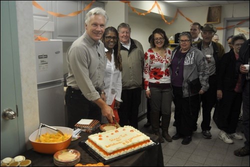 NDP candidate Glenn Tait cut the cake at his official office grand opening on 98th Street on Thursday morning. The event featured food in NDP orange colors, right down to the contents of the cake.Photos by John Cairns