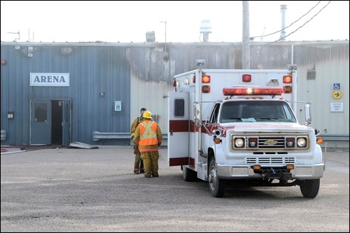 Two firefighters confer beside the fire and rescue truck outside the Saskcan Community Centre in Wilkie. The community centre caught fire the afternoon of Oct. 9 and it appears doubtful that any portion of it — the hall, hockey rink, curling rink — will be usable this winter. Photos by Helena Long