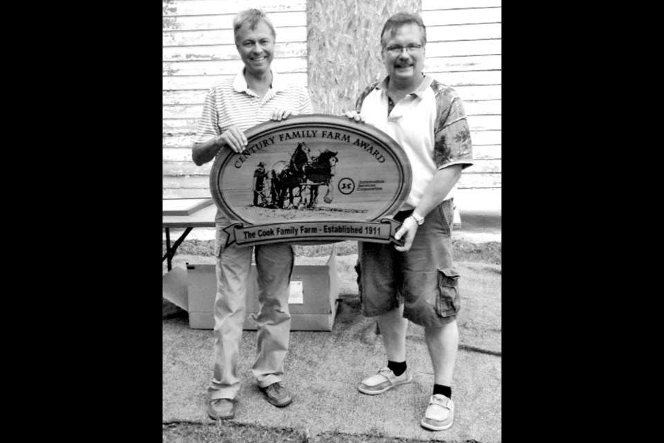 Terry Cook, left, and Bart Cook posed with the Century Family Farm 100th anniversary sign dur-ing a family gathering in Hazel Dell on July 31 to August 2.