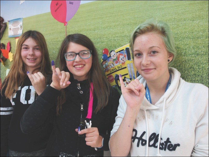 Student council leaders Alli Lytwyn, Cherity Odut and Wyntr Scheres show off their purple pinkies at École McIsaac School on Tuesday. The girls collected donations for World Polio Day. Their purple pinkies paid homage to the method used in overseas countries to ensure children who are vaccinated against polio do not receive a double dosage.
