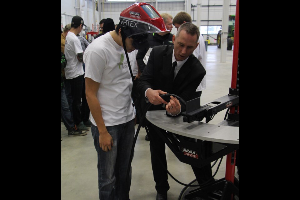 Taran Quewezance tests out the welding simulator at the grand opening of the Parkland College Trades and Technology Centre, with guidance from Andrew Bartlett from the CWA Foundation.