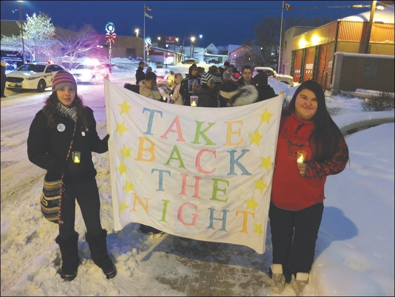 Brennlee Anderson (left) and Nadine McDermott led the march while hoisting a Take Back the Night banner.