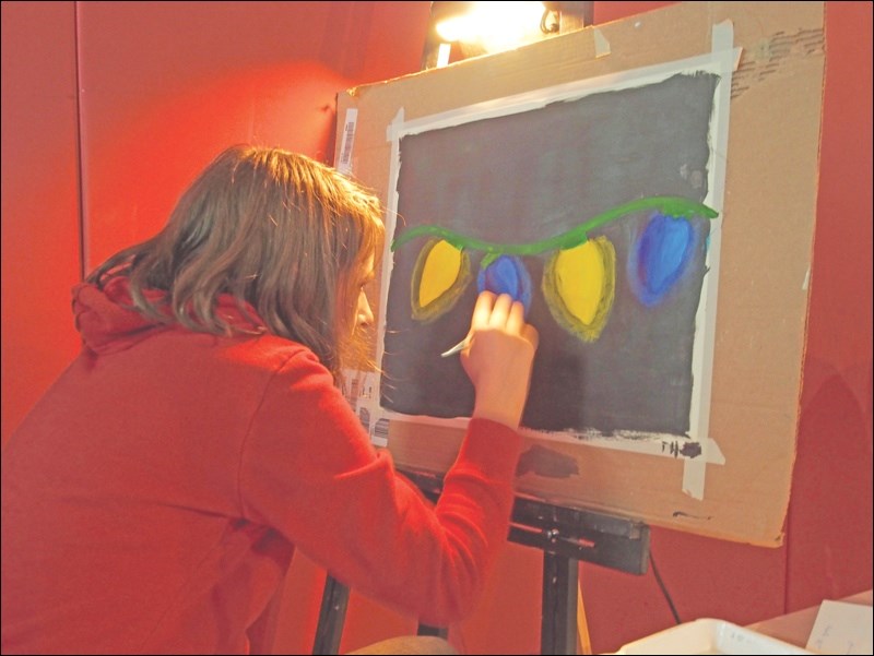 Phoenix Hanson works on an acrylic painting during the concert. Four student artists created “live art” during the show.