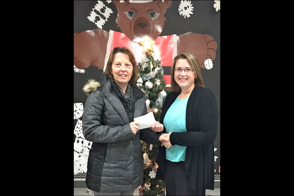 Unity Public School principal Karalyn Brown presents Unity’s Secret Santa chairperson, Sharon Riou, with $835.15. The sum represented the silver collection taken at two days of their Christmas concert, totalling $525.15, and UPS staff took up a collection raising another $310. Photo by Sherri Solomko