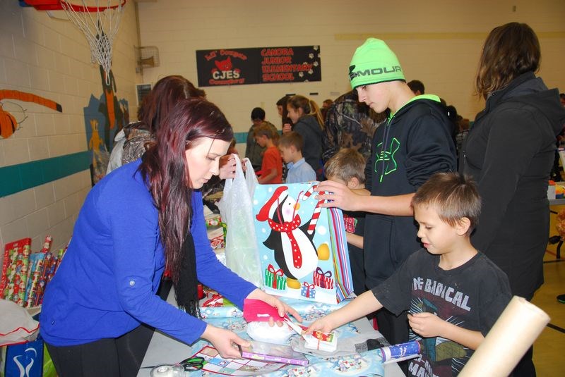 Carah Schomberg, a volunteer, helped Connor Nordin wrap his Christmas gifts during the CJES Recycled Christmas Gift Exchange on December 9.