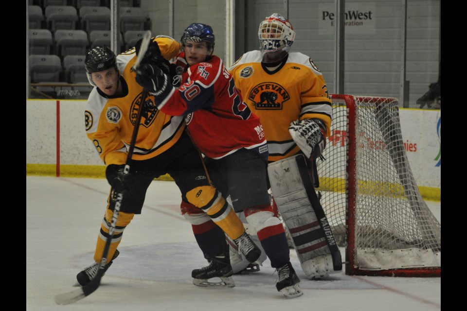 Estevan Bruins defenceman Zach Douglas battles with Melville Millionaires forward Christian Stevens for position in front of Daniel Wapple's net.