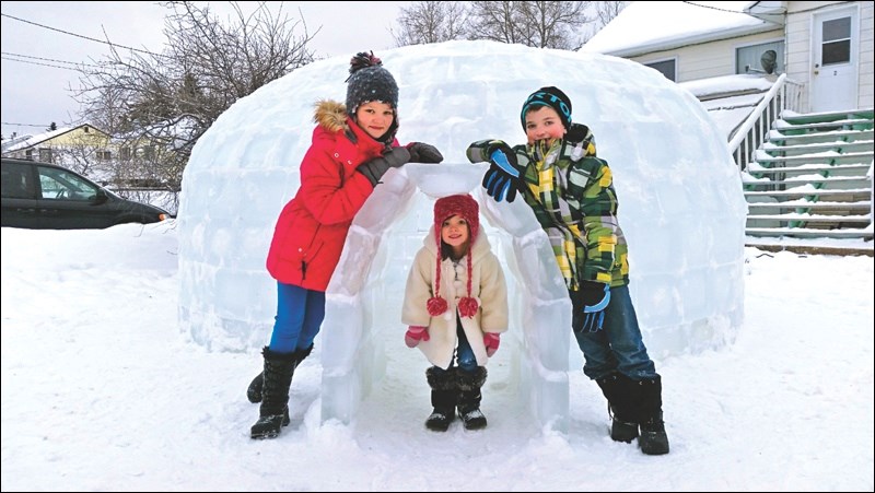 Lexus Altman (from left), sister Bella and brother Micha pose at the ice igloo they helped their parents build in the front yard of their Creighton Avenue home.