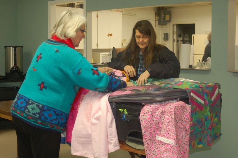 Aileen Lubiniecki and Barb Biccum helped pack a suitcase full of dresses and other clothing that was to be sent to Africa for a program to assist children on January 14.